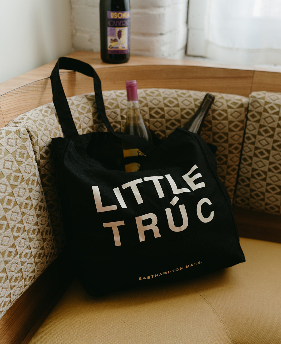 black tote bag with little truc, easthampton mass text on it filled with wine bottles.